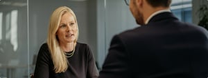 Corporate photo for Sophie de Jong having a conversation with another person who is sitting across from her at a table. Sophie is setting on the opposite side of the table, left on the photo. We are looking at the back 